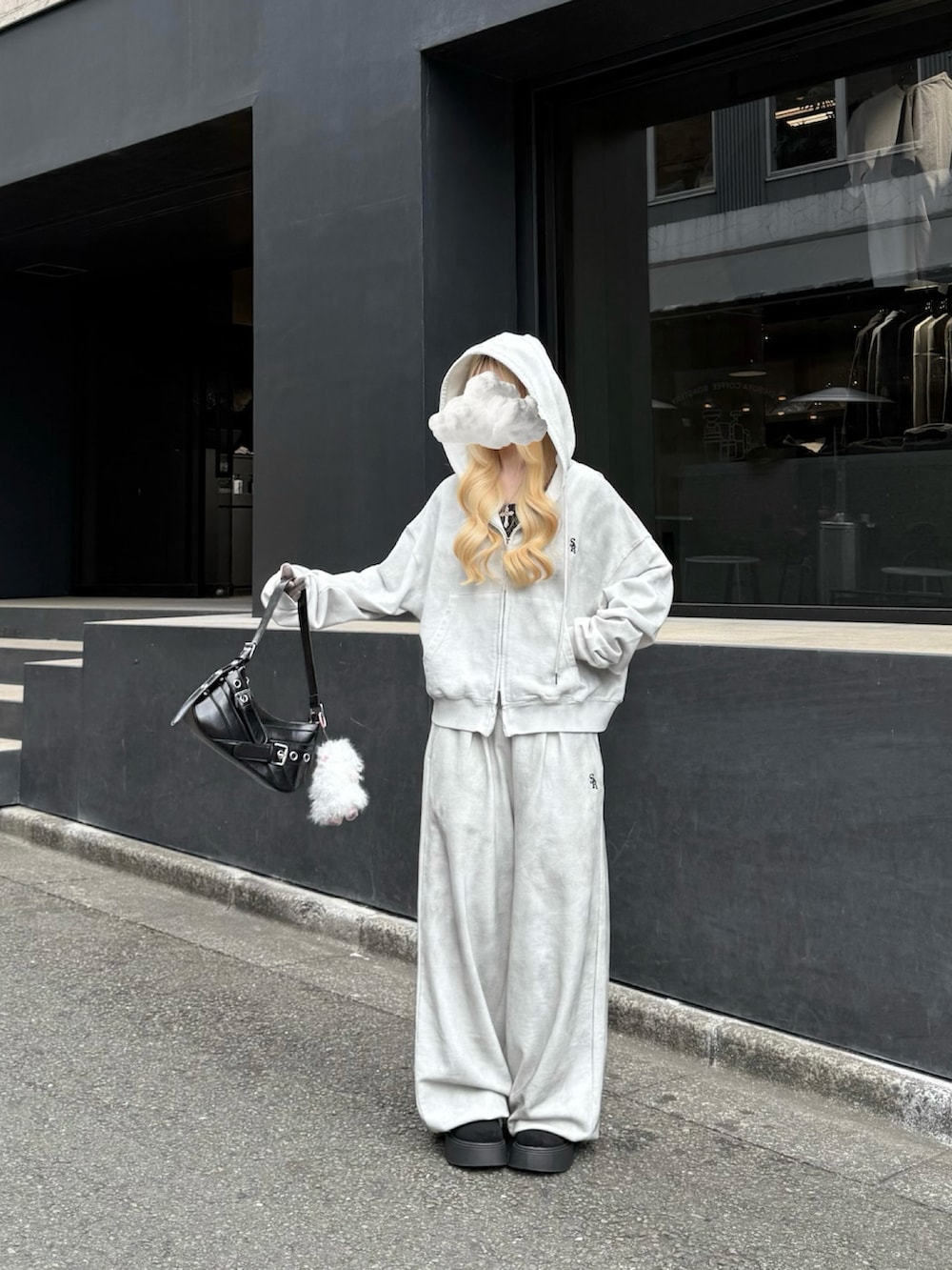 グレー系のパーカー、グレー系のスウェットパンツ、ブラック系のハンドバッグを着用したレディースの冬コーディネートの2枚目の写真