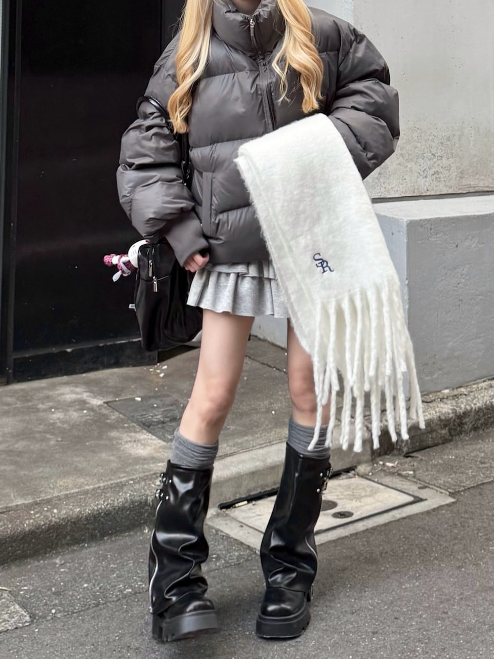 グレー系のスカート、ブラック系のボストンバッグ、グレー系のダウンジャケット/コートを着用したレディースの秋コーディネートの2枚目の写真