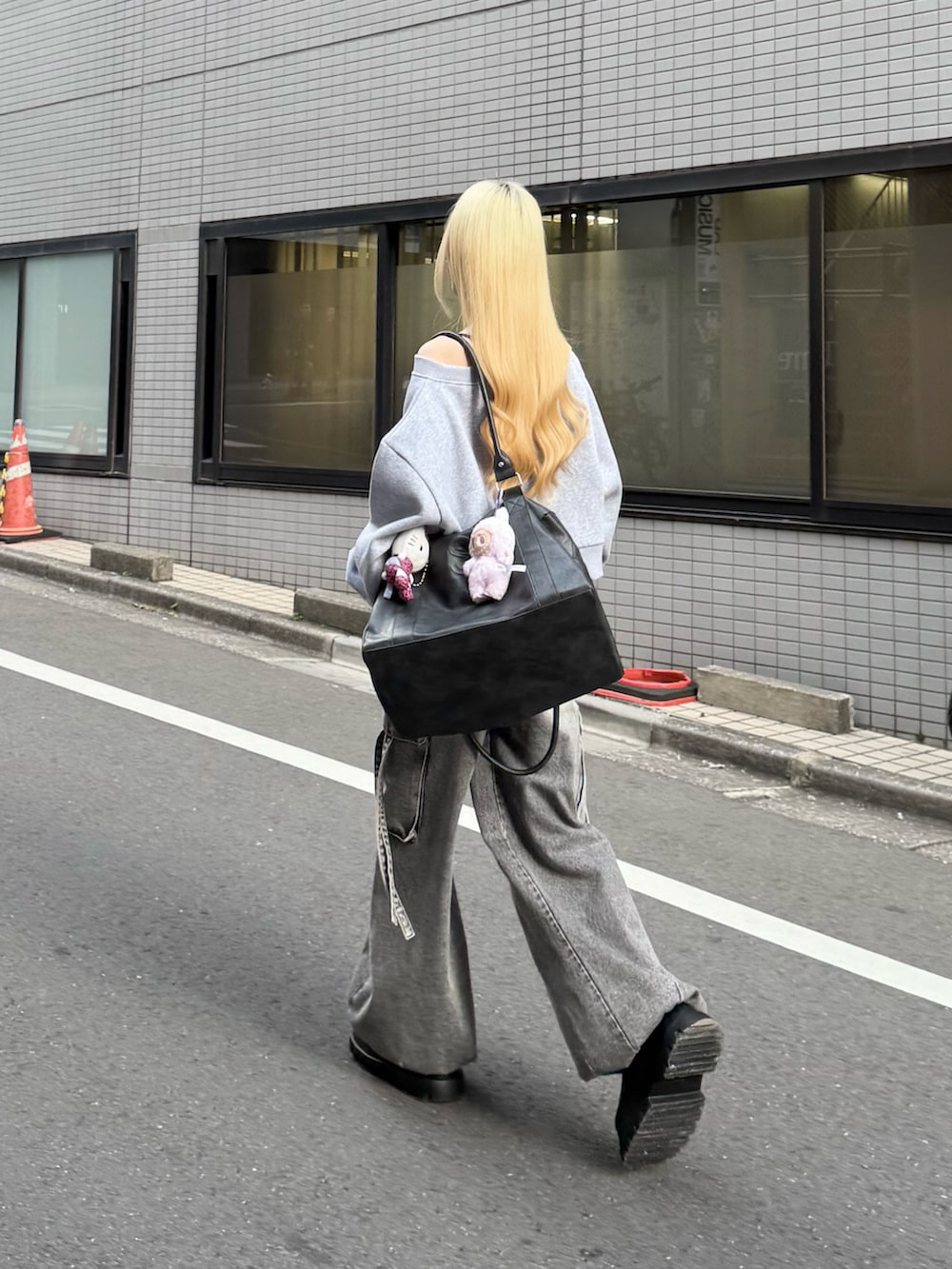 グレー系のスウェット、グレー系のデニムパンツ、ブラック系のボストンバッグを着用したレディースの冬コーディネートの2枚目の写真