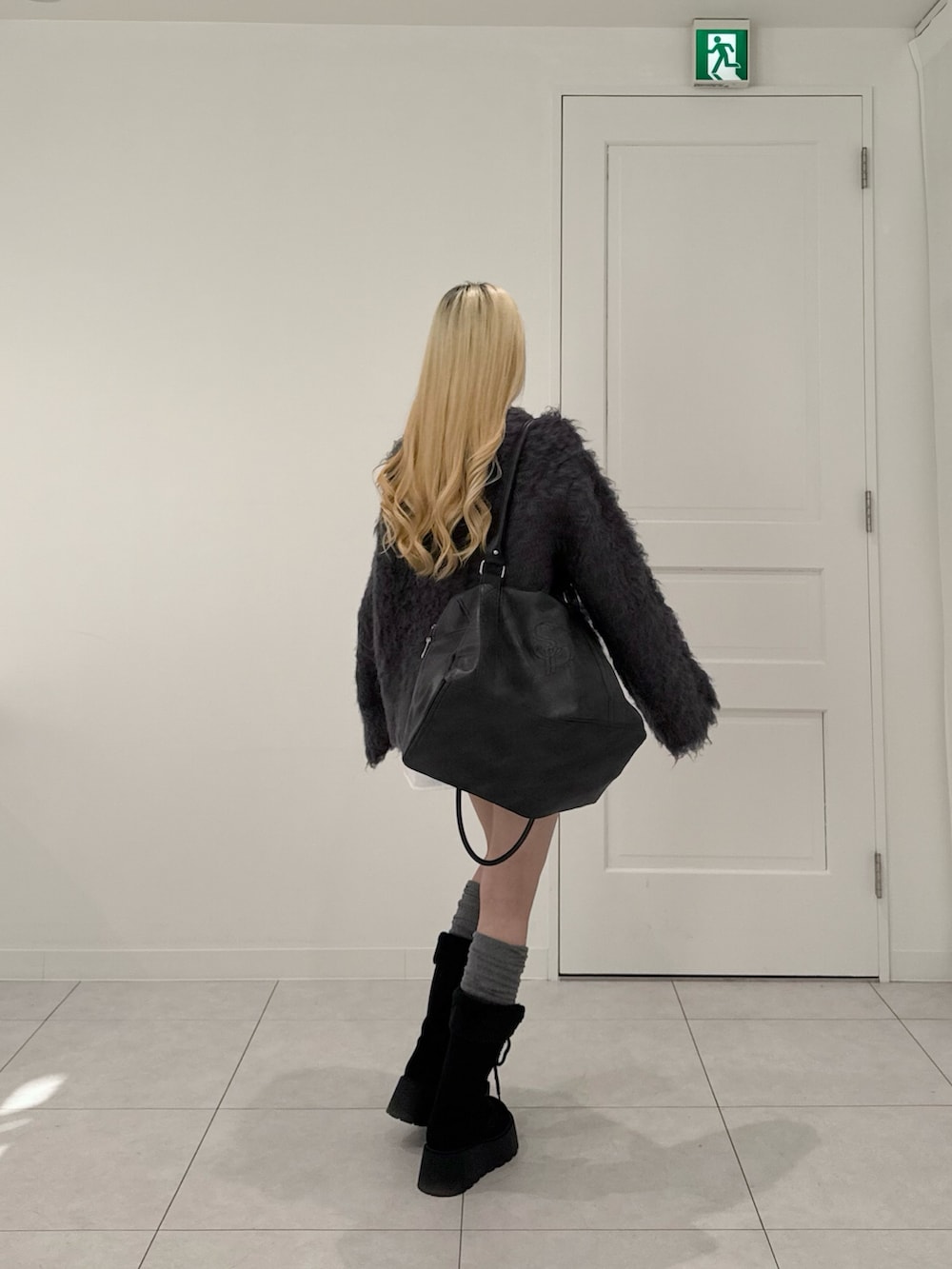 グレー系のカーディガン/ボレロ、グレー系のスカート、ブラック系のボストンバッグを着用したレディースの冬コーディネートの3枚目の写真