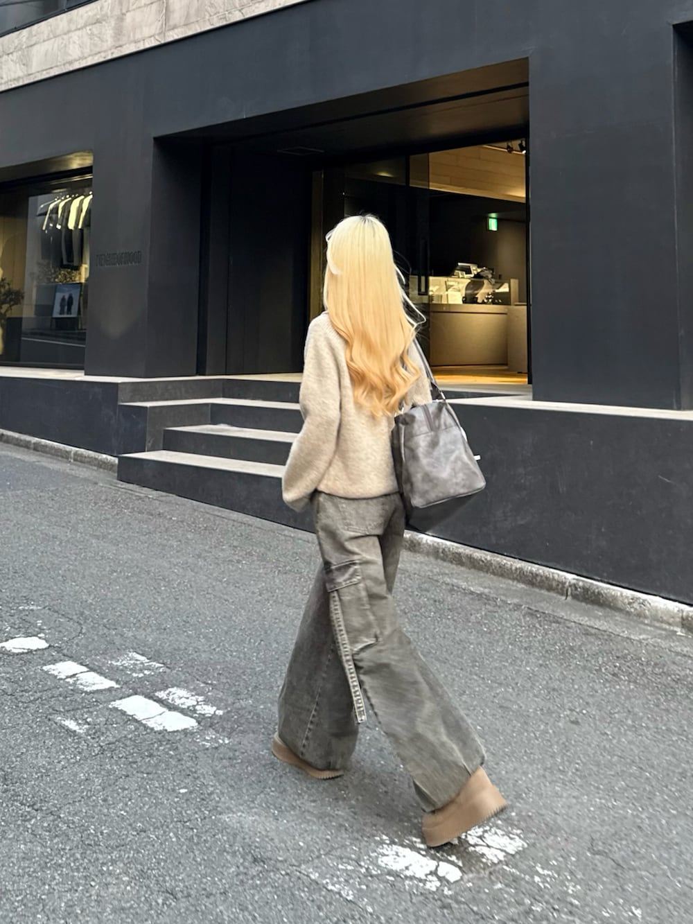 ベージュ系のニット/セーター、グレー系のボストンバッグ、ブラウン系のデニムパンツを着用したレディースの冬コーディネートの4枚目の写真