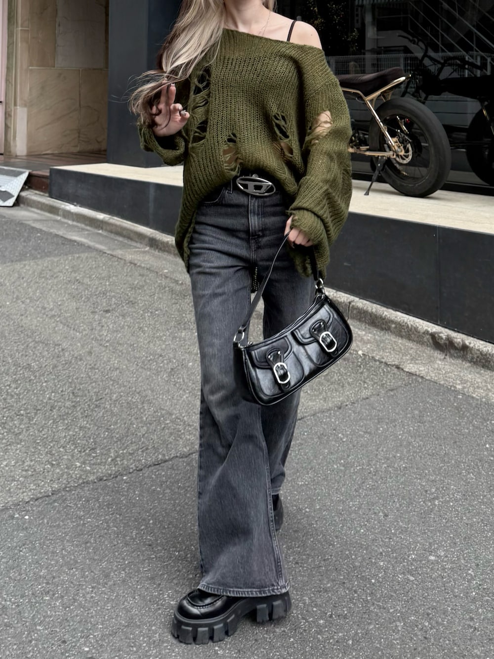 グリーン系のニット/セーター、ブラック系のショルダーバッグ、ブラック系のデニムパンツを着用したレディースの秋コーディネートの2枚目の写真