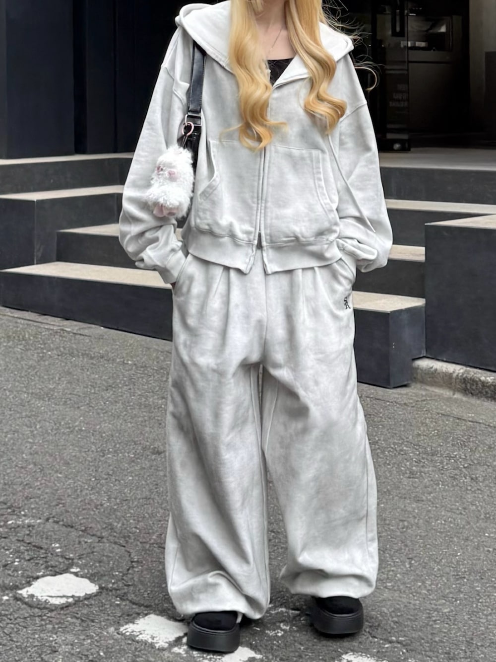 グレー系のパーカー、グレー系のスウェットパンツ、ブラック系のハンドバッグを着用したレディースの冬コーディネートの3枚目の写真