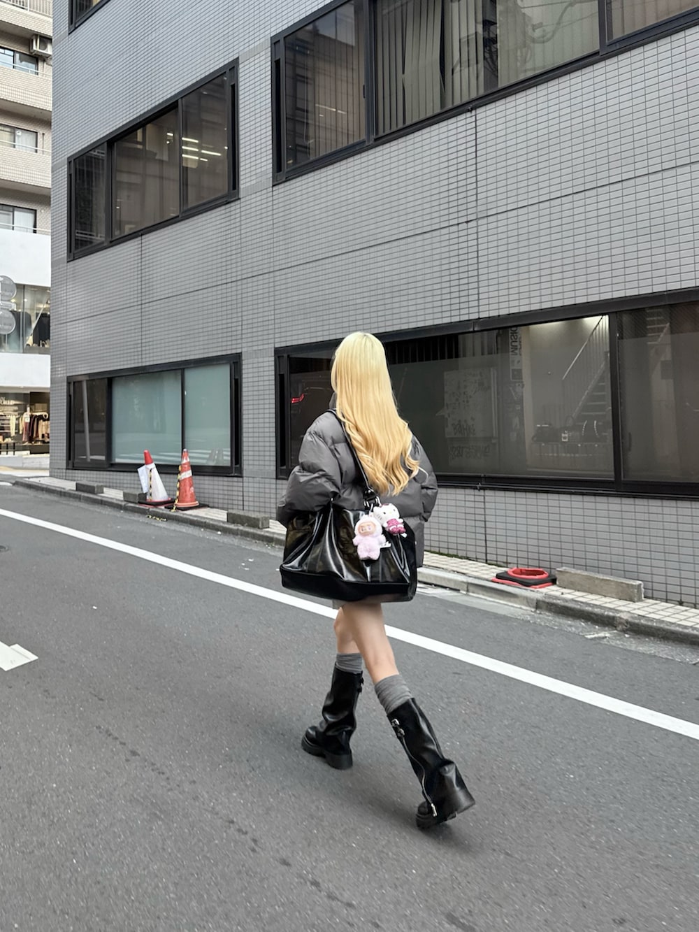 グレー系のスカート、ブラック系のボストンバッグ、グレー系のダウンジャケット/コートを着用したレディースの秋コーディネートの4枚目の写真