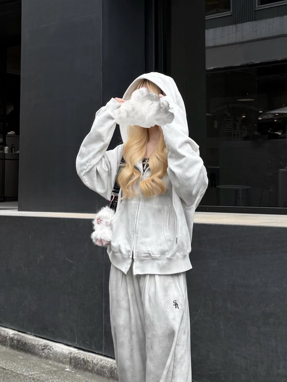 グレー系のパーカー、グレー系のスウェットパンツ、ブラック系のハンドバッグを着用したレディースの冬コーディネートの5枚目の写真