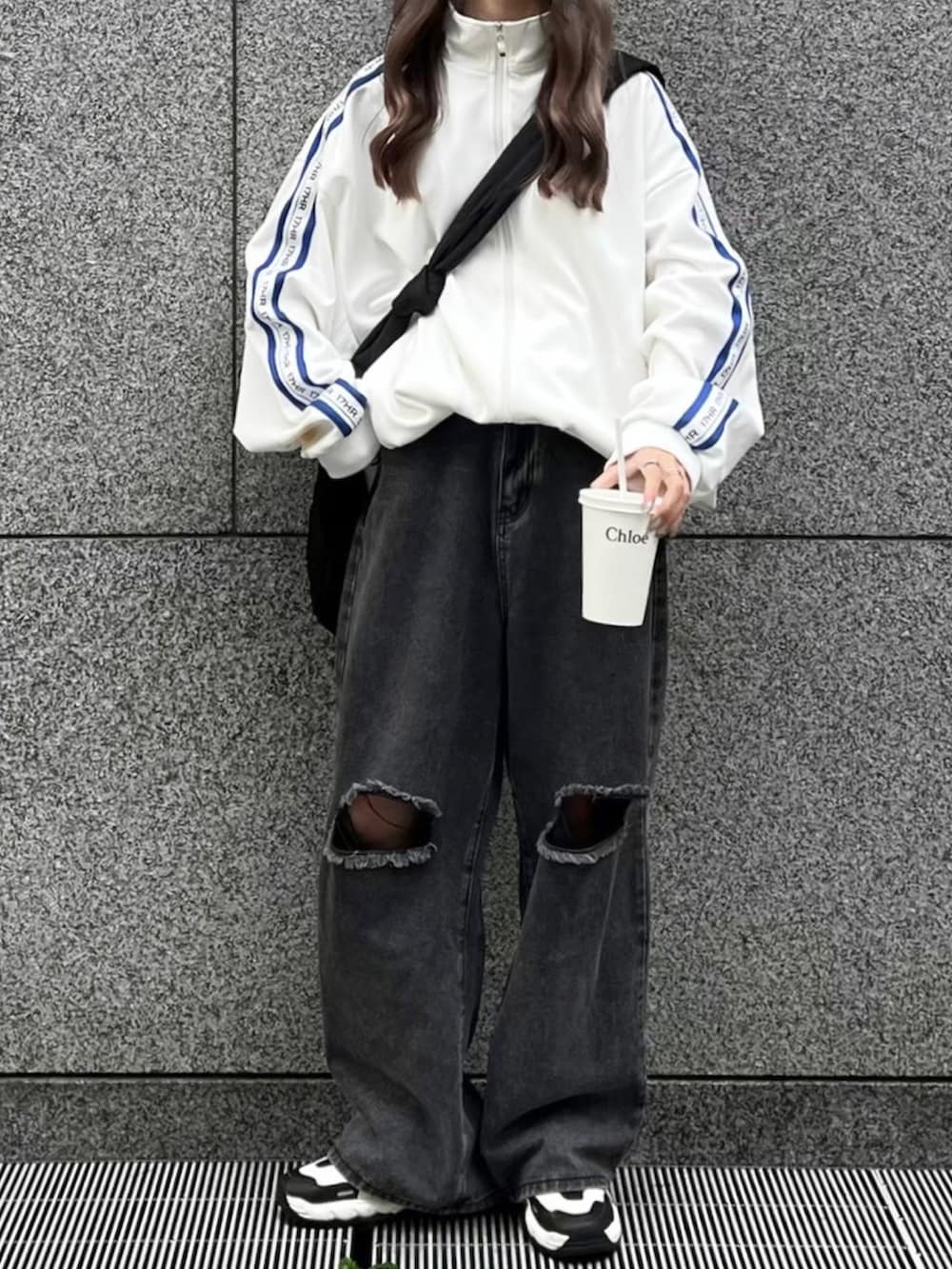 ホワイト系のジャージ、ブラック系のショルダーバッグ、ブラック系のデニムパンツを着用したレディースの冬コーディネートの2枚目の写真