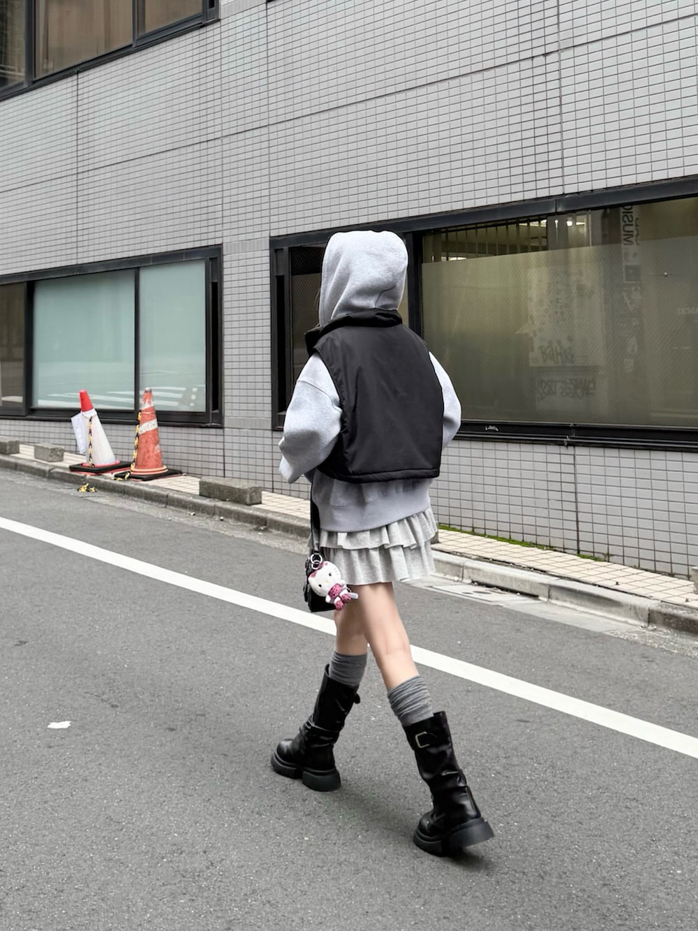 グレー系のパーカー、グレー系のスカート、ブラック系のショルダーバッグを着用したレディースの秋コーディネートの4枚目の写真