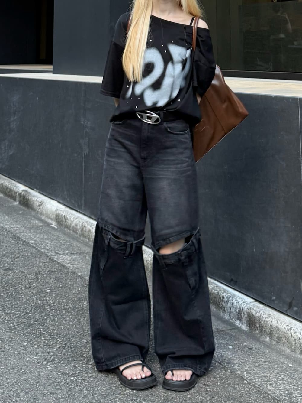 ブラック系のデニムパンツ、ブラック系のTシャツ/カットソー、ブラウン系のボストンバッグを着用したレディースの秋コーディネートの3枚目の写真