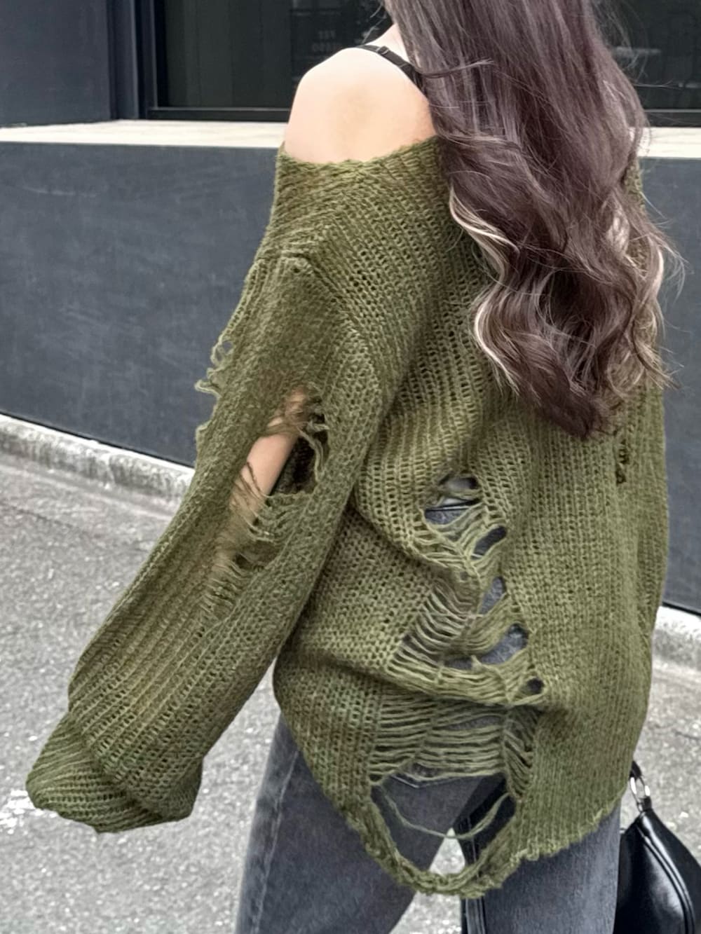 グリーン系のニット/セーター、ブラック系のショルダーバッグ、ブラック系のデニムパンツを着用したレディースの秋コーディネートの4枚目の写真