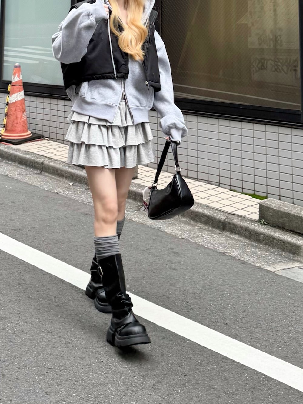 グレー系のパーカー、グレー系のスカート、ブラック系のショルダーバッグを着用したレディースの秋コーディネートの2枚目の写真