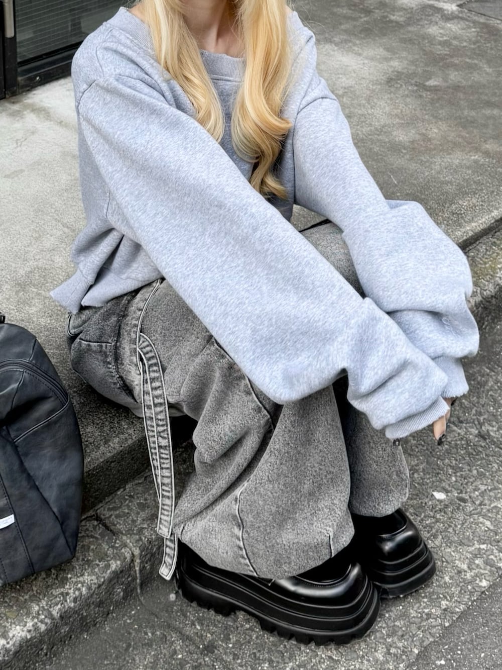 グレー系のスウェット、グレー系のデニムパンツ、ブラック系のボストンバッグを着用したレディースの冬コーディネートの3枚目の写真