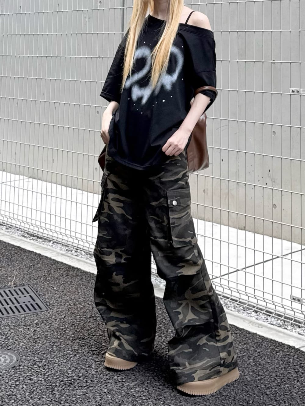 ブラック系のTシャツ/カットソー、その他のカーゴパンツ、ブラウン系のボストンバッグを着用したレディースの夏コーディネートの2枚目の写真