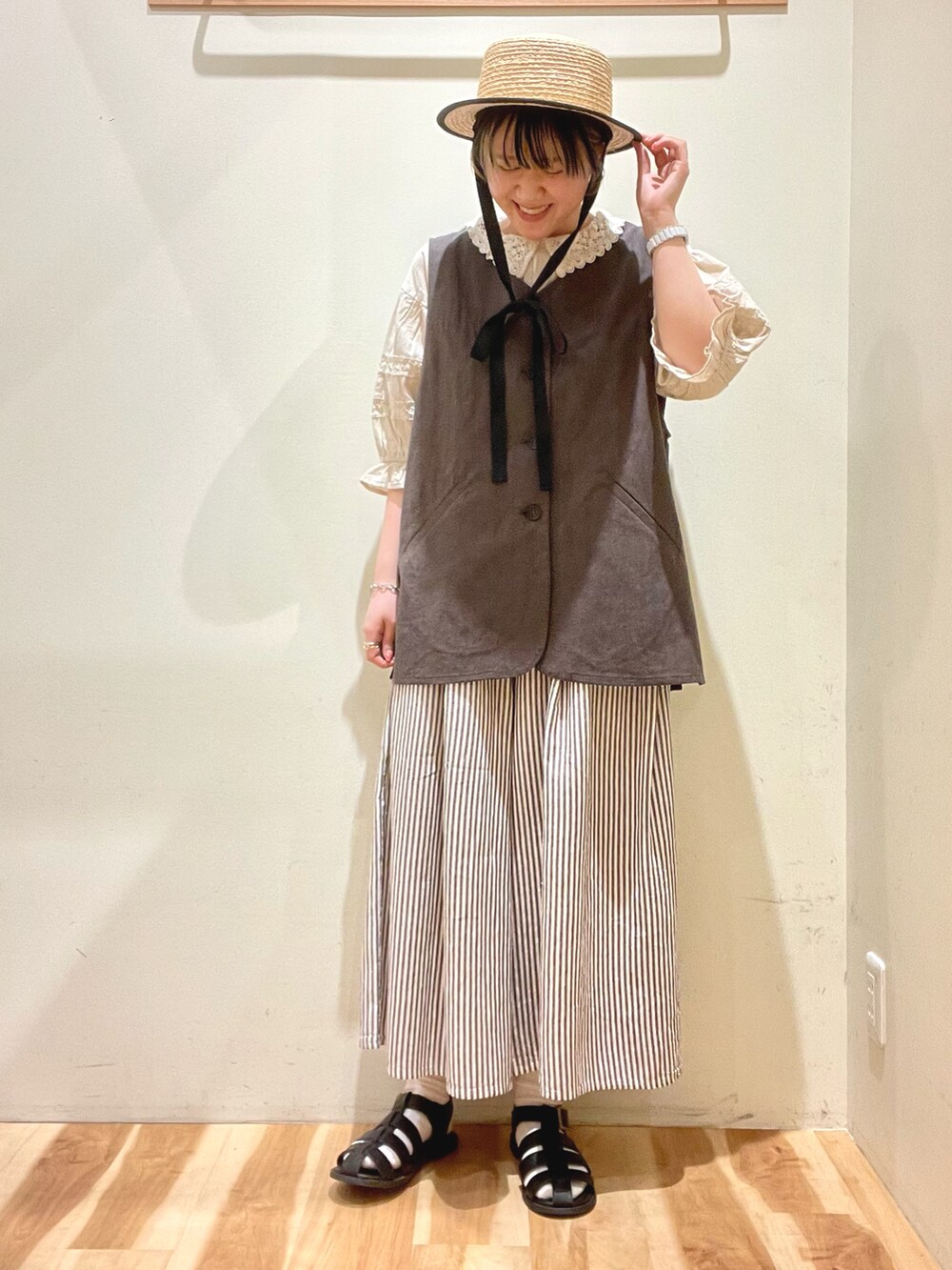 ベージュ系のシャツ/ブラウス、ブラック系のサンダル、ブラウン系のベストを着用したレディースの春コーディネートの2枚目の写真