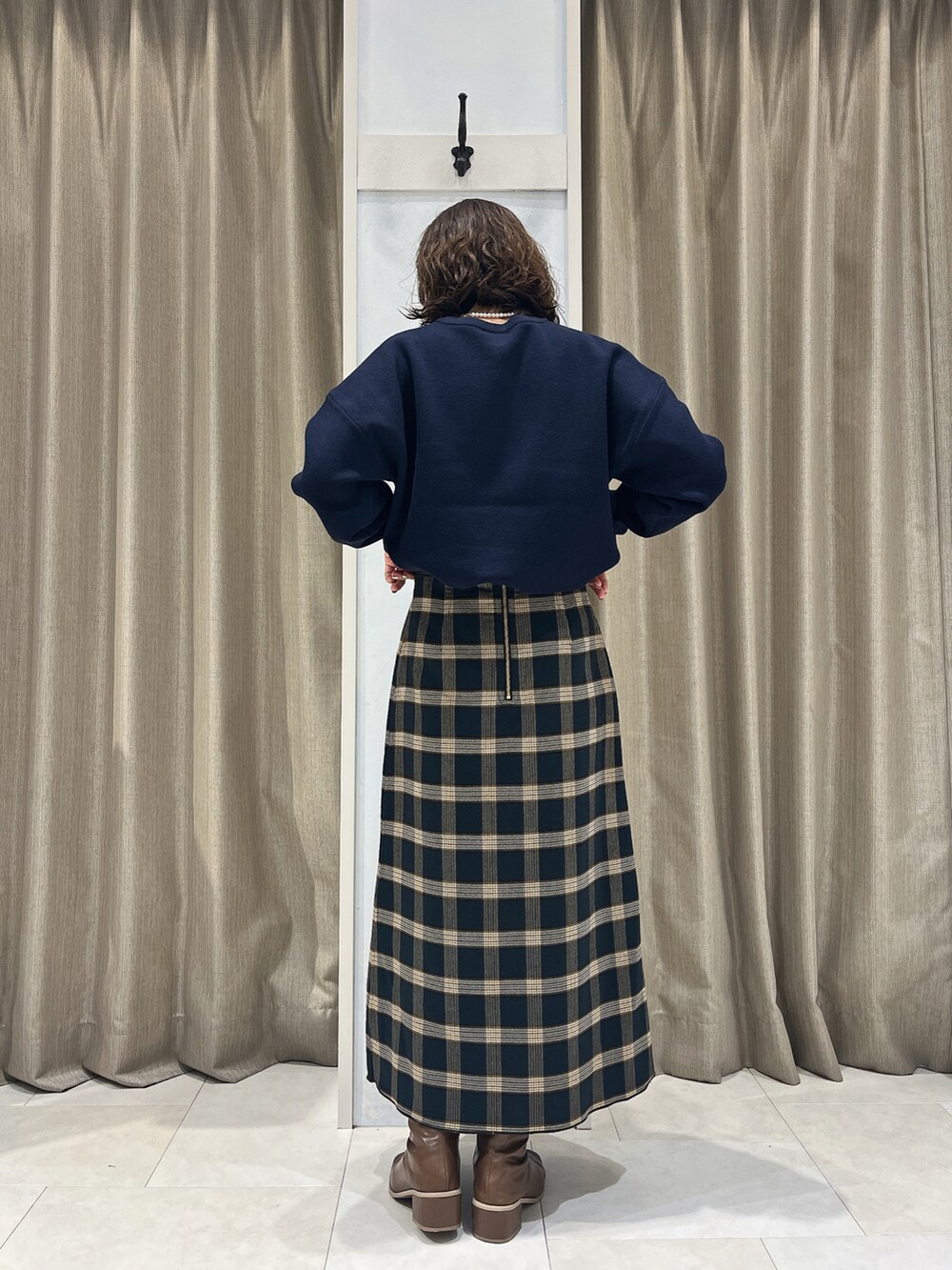 ブルー系のニット/セーター、グリーン系のスカート、ベージュ系のハンドバッグを着用したレディースの秋コーディネートの2枚目の写真