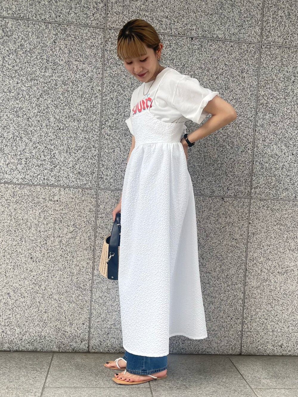 ホワイト系のワンピース、ブルー系のデニムパンツ、ベージュ系のバッグを着用したレディースの春コーディネートの2枚目の写真