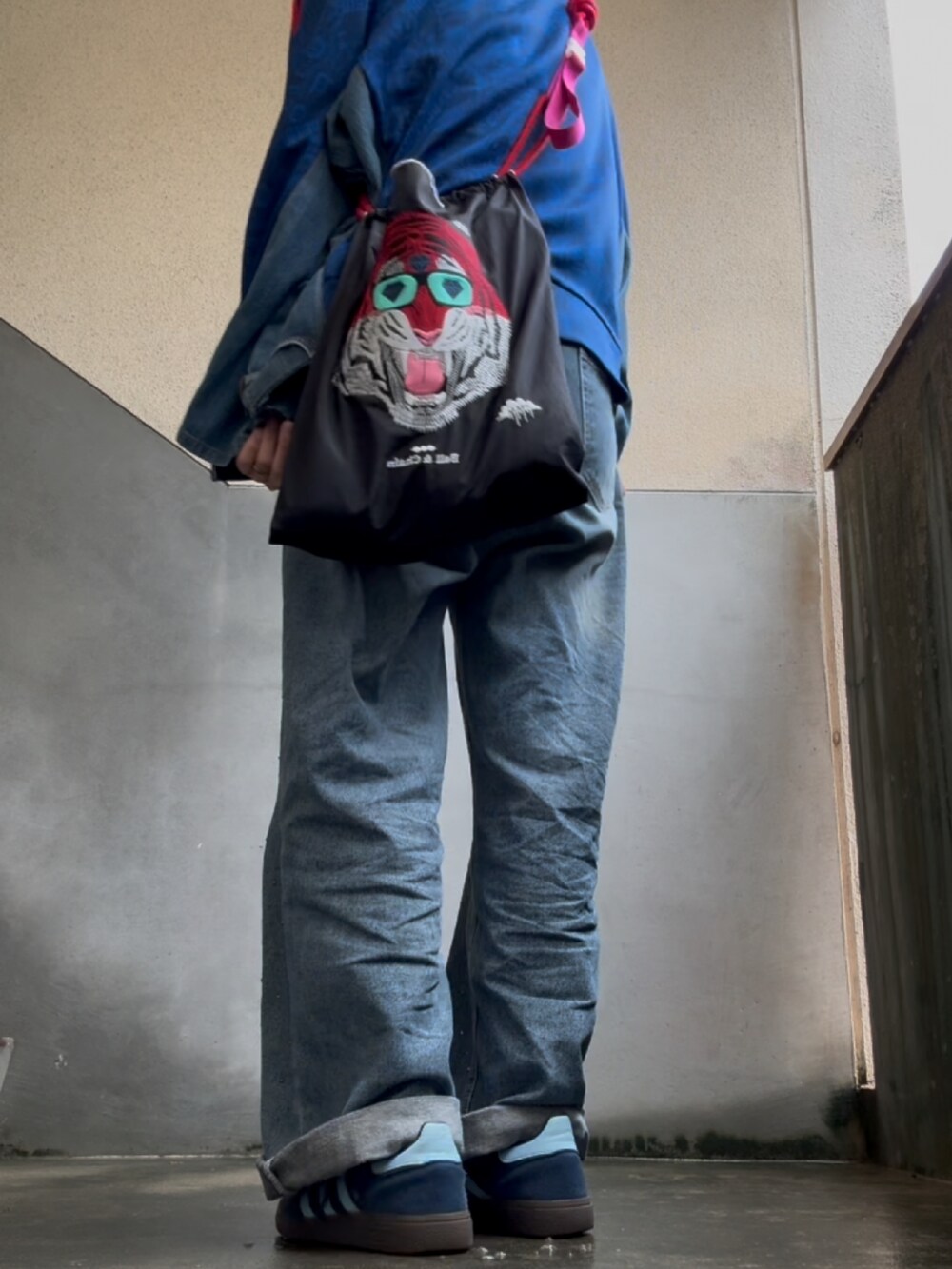 ブルー系のスニーカー、ブルー系のデニムパンツ、ブラック系のエコバッグ/サブバッグを着用したレディースの春コーディネートの3枚目の写真