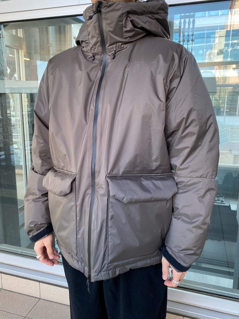 グレー系のダウンジャケット/コート、ブラック系のスリッポン、ブルー系のその他パンツを着用したメンズの秋コーディネートの2枚目の写真