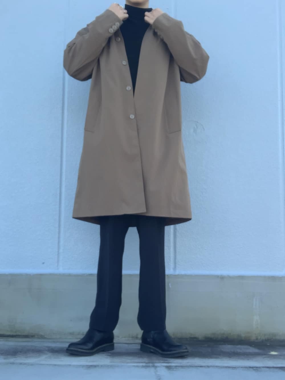 ブラック系のスラックス、ブラック系のブーツ、ベージュ系のステンカラーコートを着用したメンズの冬コーディネートの4枚目の写真