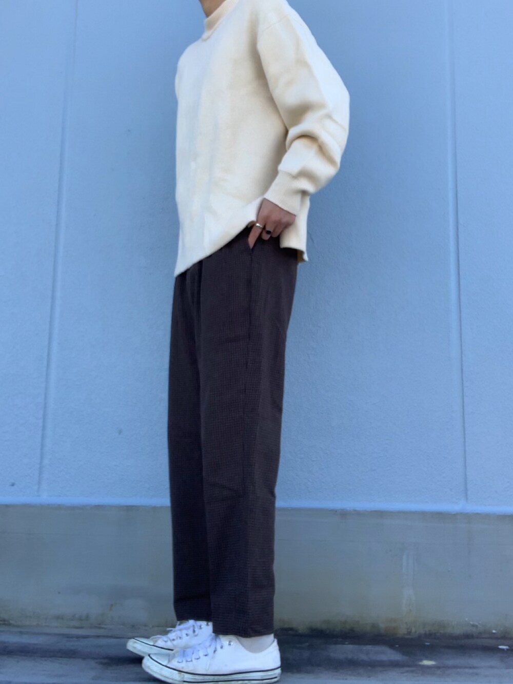 ブラウン系のスラックス、ベージュ系のニット/セーター、ホワイト系のスニーカーを着用したメンズの冬コーディネートの2枚目の写真