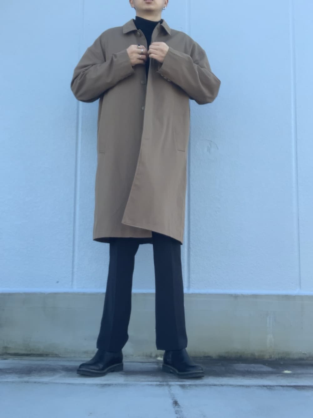 ブラック系のスラックス、ブラック系のブーツ、ベージュ系のステンカラーコートを着用したメンズの冬コーディネートの3枚目の写真