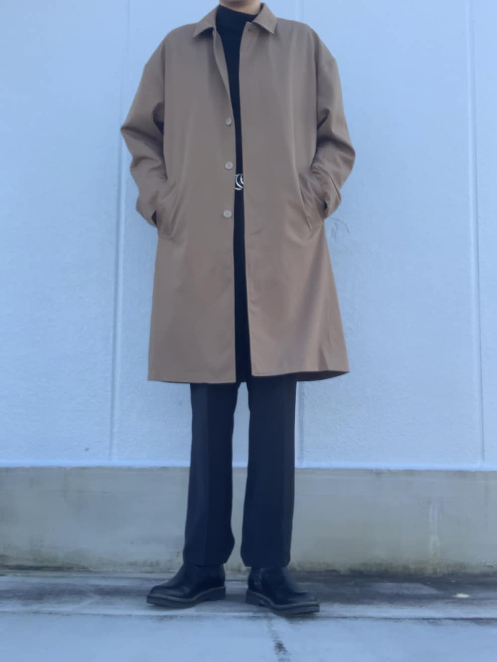 ブラック系のスラックス、ブラック系のブーツ、ベージュ系のステンカラーコートを着用したメンズの冬コーディネートの5枚目の写真