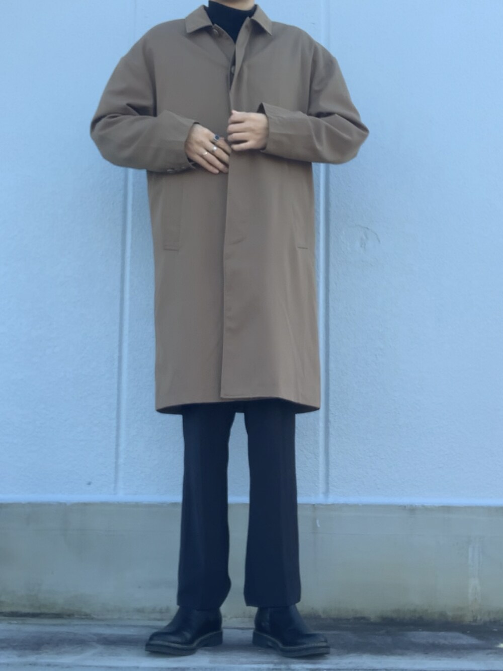 ブラック系のスラックス、ブラック系のブーツ、ベージュ系のステンカラーコートを着用したメンズの冬コーディネートの2枚目の写真