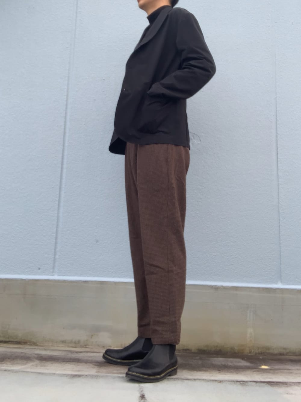 ブラック系のTシャツ/カットソー、ブラック系のジャケット/アウター、ブラウン系のスラックスを着用したメンズの冬コーディネートの4枚目の写真