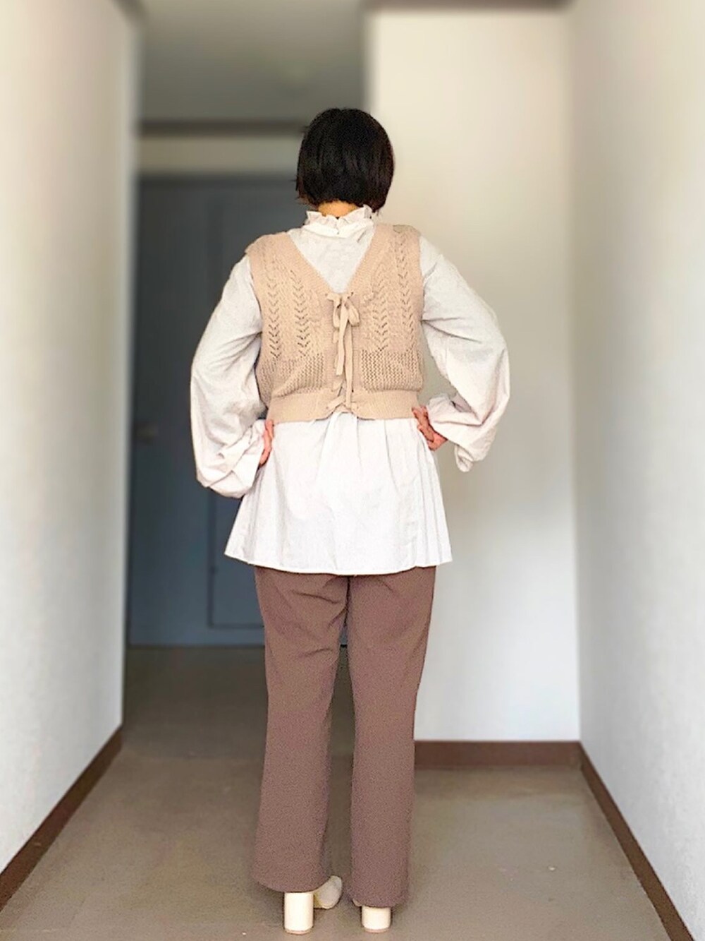 ブラウン系のスラックス、ベージュ系のベスト、ベージュ系のワンピースを着用したレディースの冬コーディネートの2枚目の写真