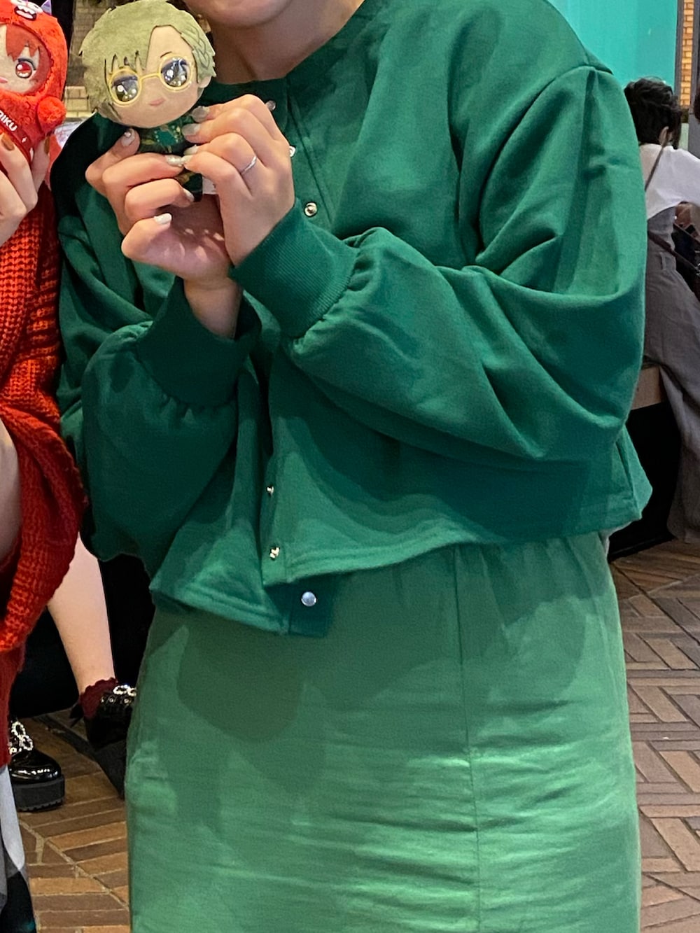 グリーン系のスカート、ベージュ系のスニーカー、グリーン系のカーディガン/ボレロを着用したレディースの秋コーディネートの2枚目の写真