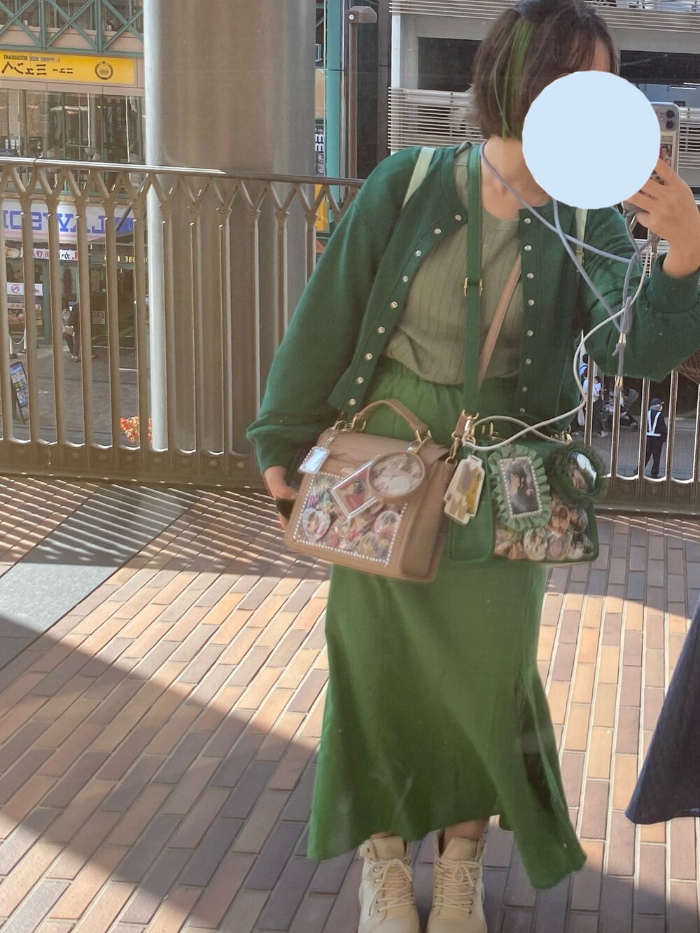 グリーン系のスカート、ベージュ系のスニーカー、グリーン系のカーディガン/ボレロを着用したレディースの秋コーディネートの3枚目の写真