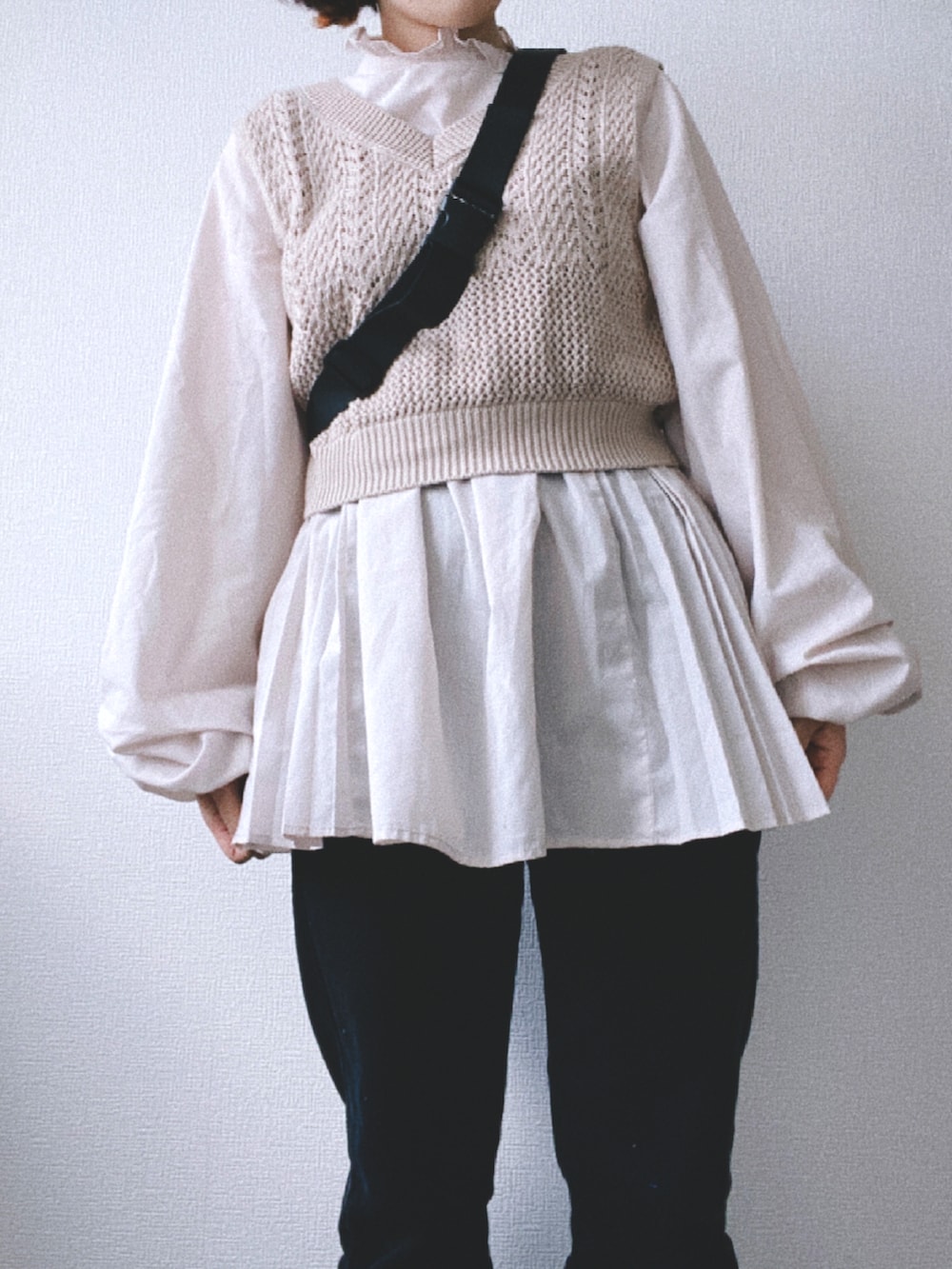 ブラック系のデニムパンツ、ベージュ系のワンピース、ベージュ系のベストを着用したレディースの春コーディネートの4枚目の写真