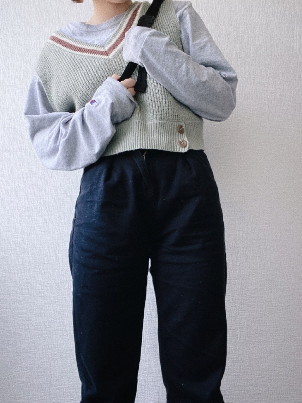 ブラック系のボディバッグ/ウエストポーチ、グリーン系のベスト、グレー系のTシャツ/カットソーを着用したレディースの春コーディネートの2枚目の写真