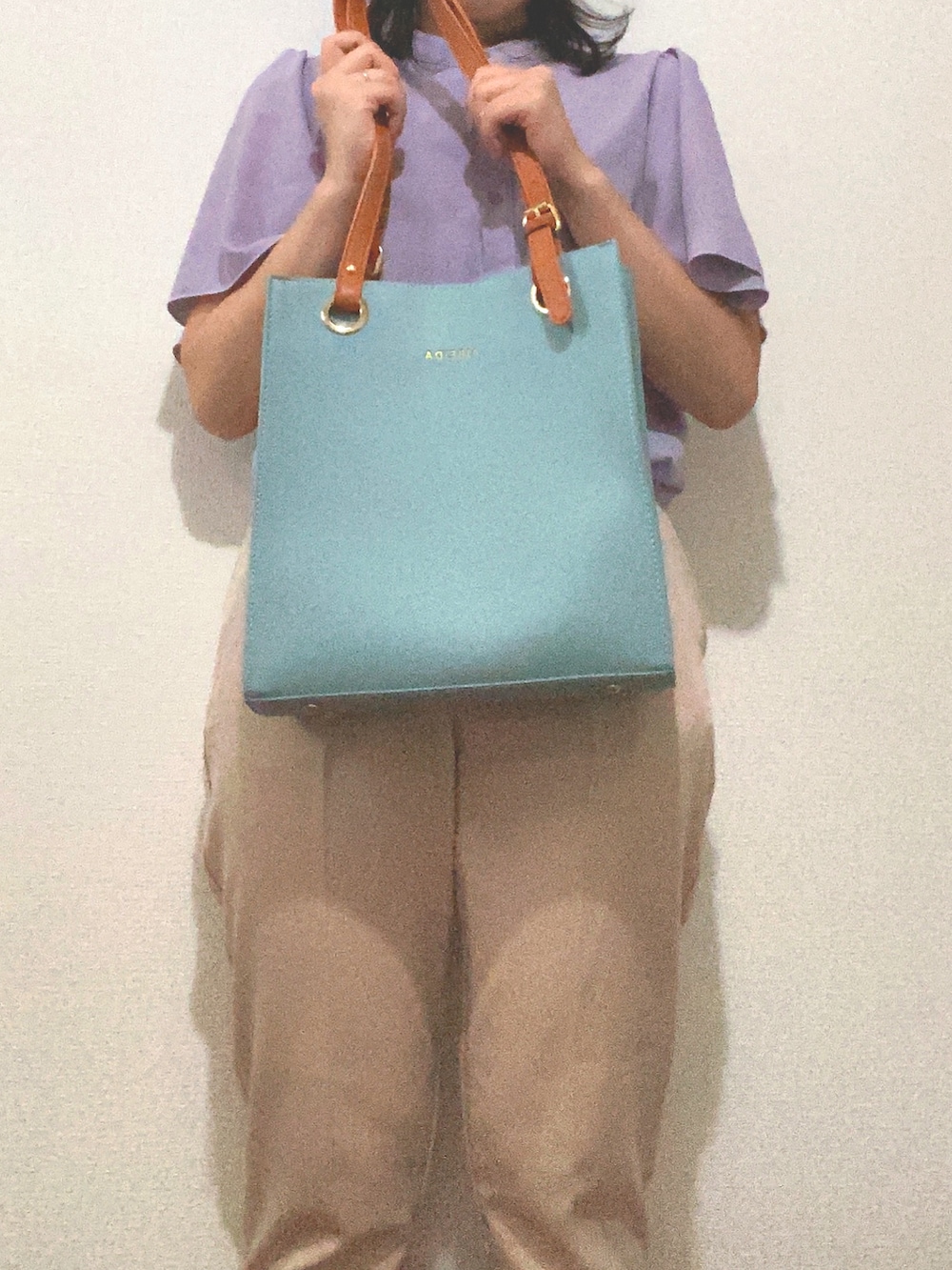 ベージュ系のスラックス、ブルー系のハンドバッグ、パープル系のシャツ/ブラウスを着用したレディースの夏コーディネートの4枚目の写真