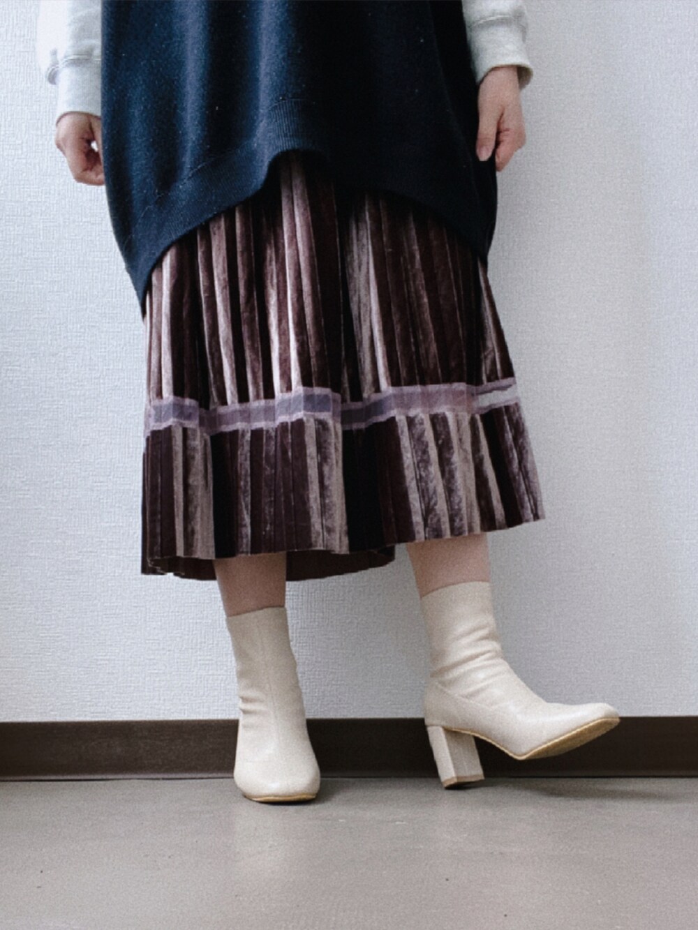 ブラック系のベスト、ブラウン系のスカート、グレー系のスウェットを着用したレディースの春コーディネートの4枚目の写真