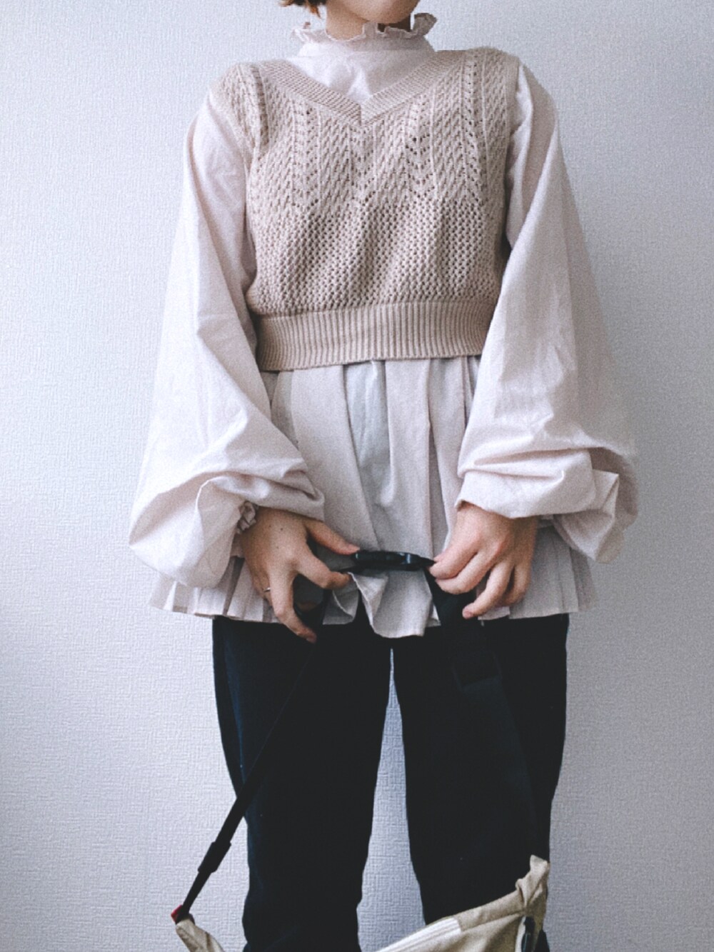 ブラック系のデニムパンツ、ベージュ系のワンピース、ベージュ系のベストを着用したレディースの春コーディネートの3枚目の写真