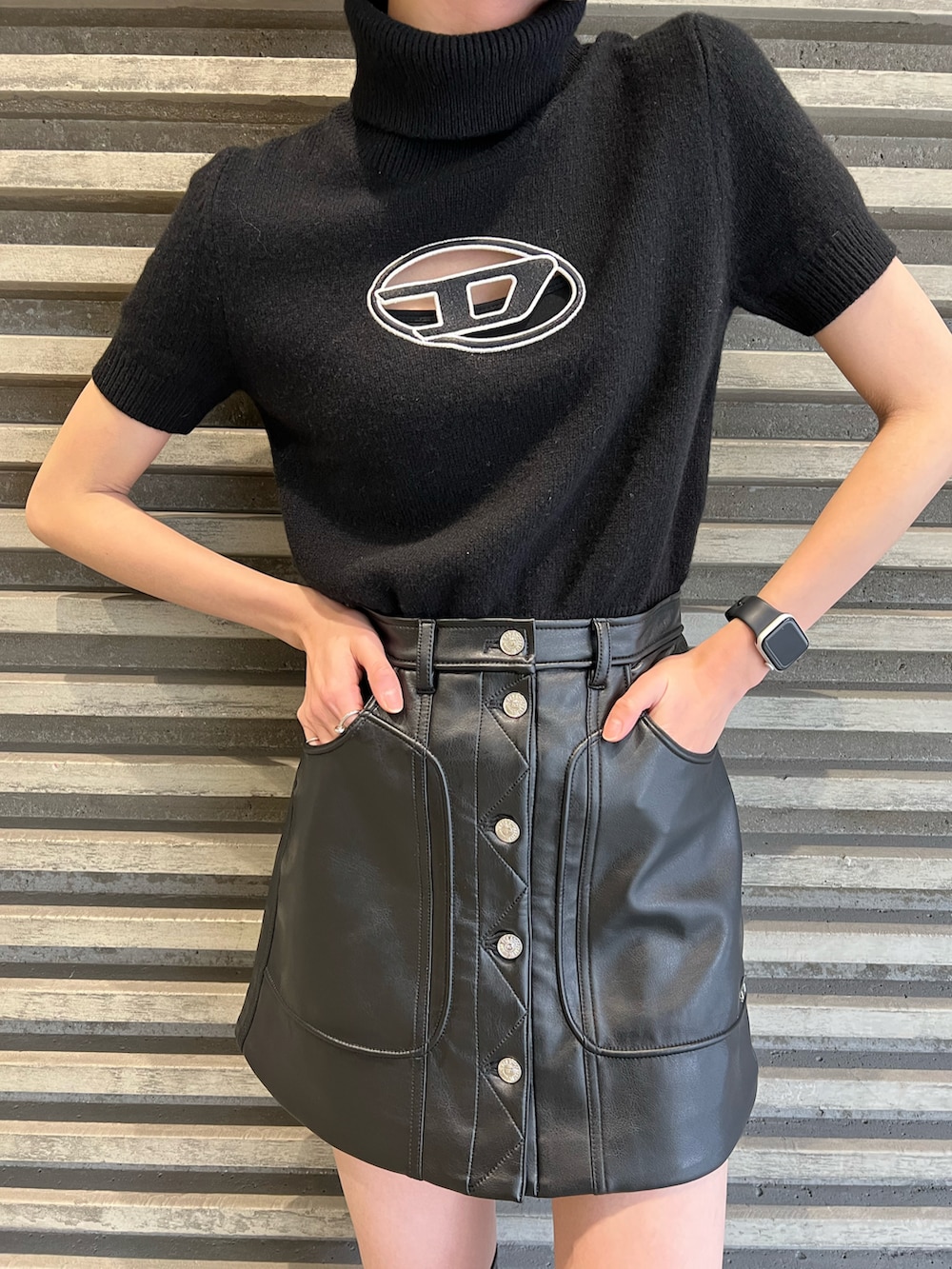 ブラック系のニット/セーター、ブラック系のスカート、ピンク系のハンドバッグを着用したレディースの冬コーディネートの2枚目の写真