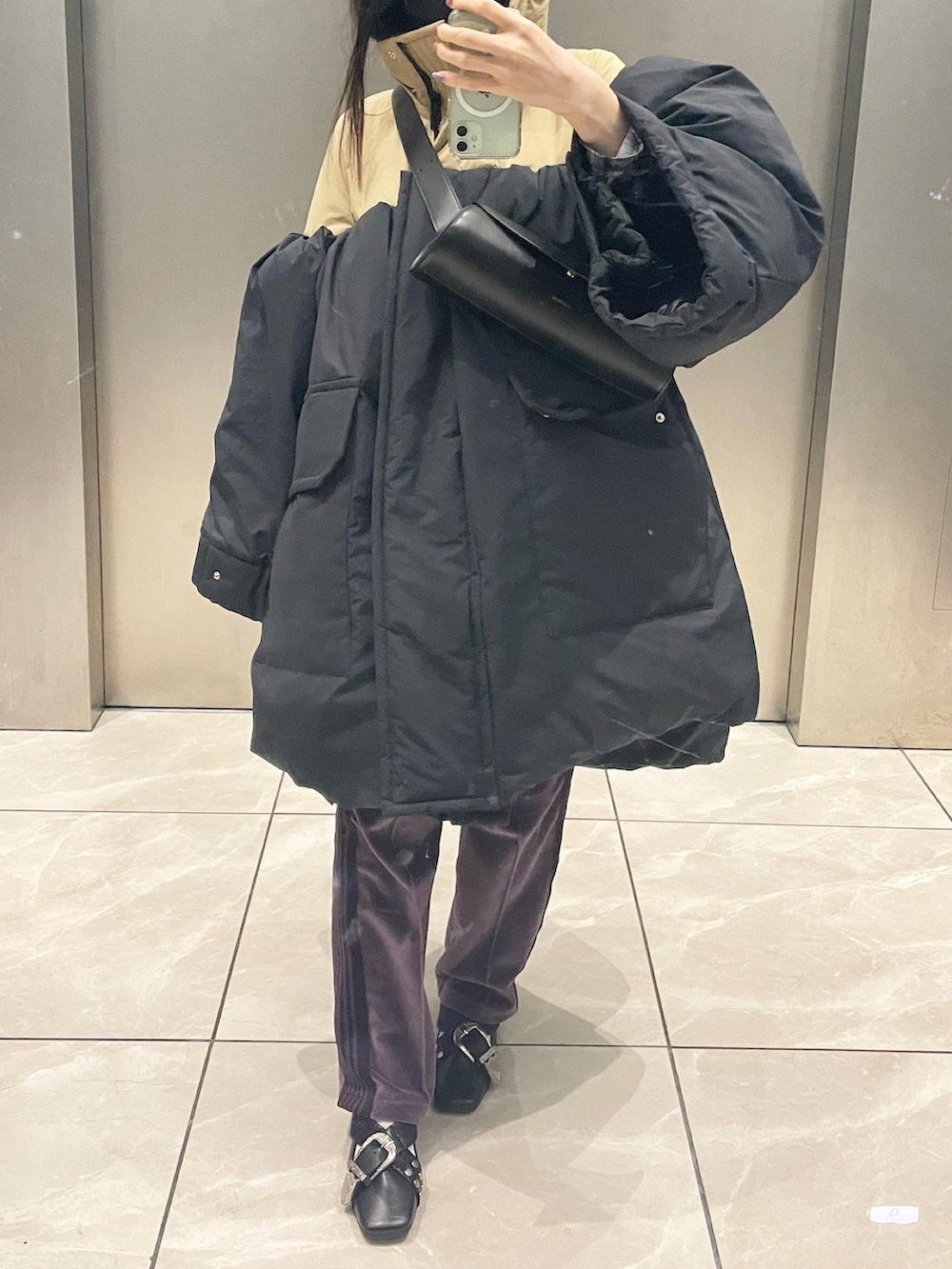 パープル系のパンツ、ブラック系のシューズ、ブラック系のショルダーバッグを着用したレディースの冬コーディネートの3枚目の写真