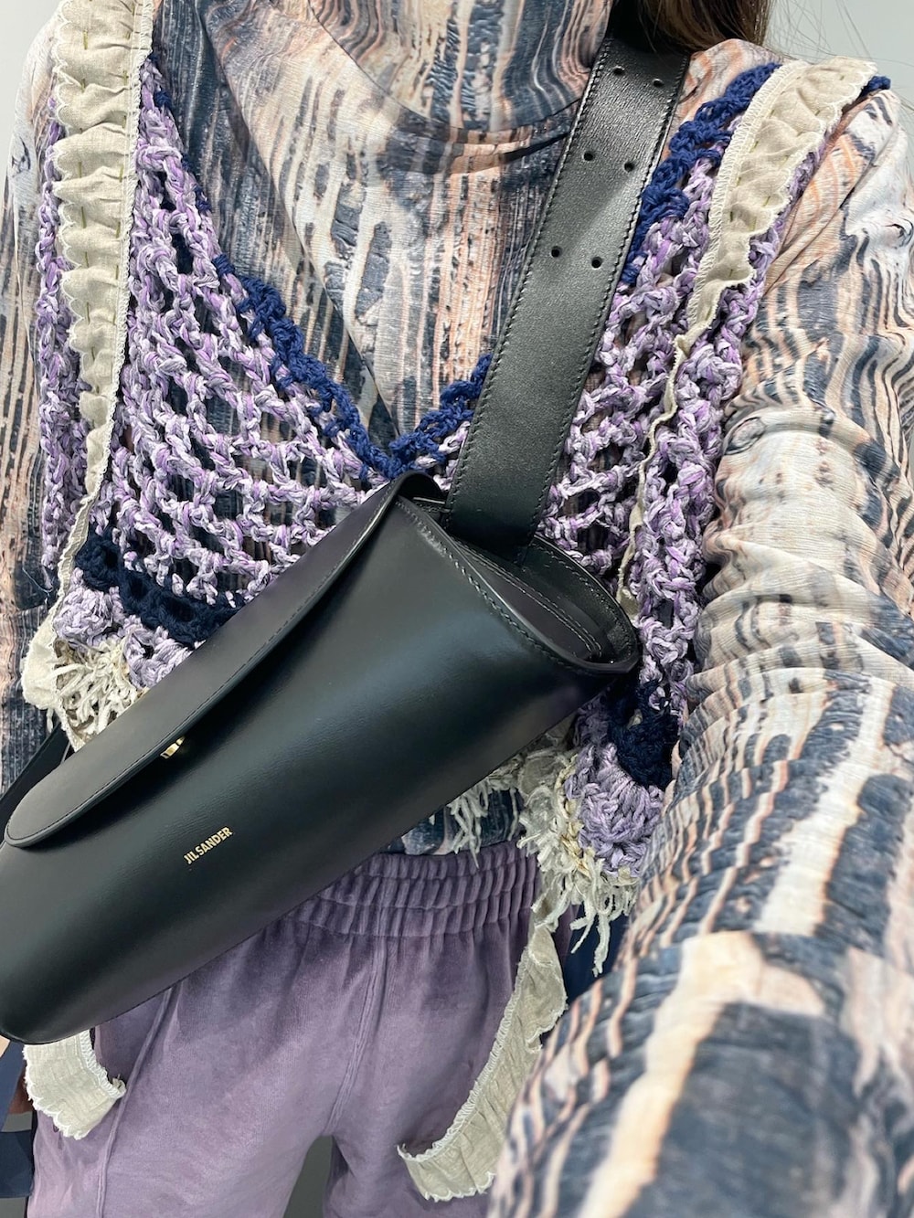 パープル系のパンツ、ブラック系のシューズ、ブラック系のショルダーバッグを着用したレディースの冬コーディネートの2枚目の写真