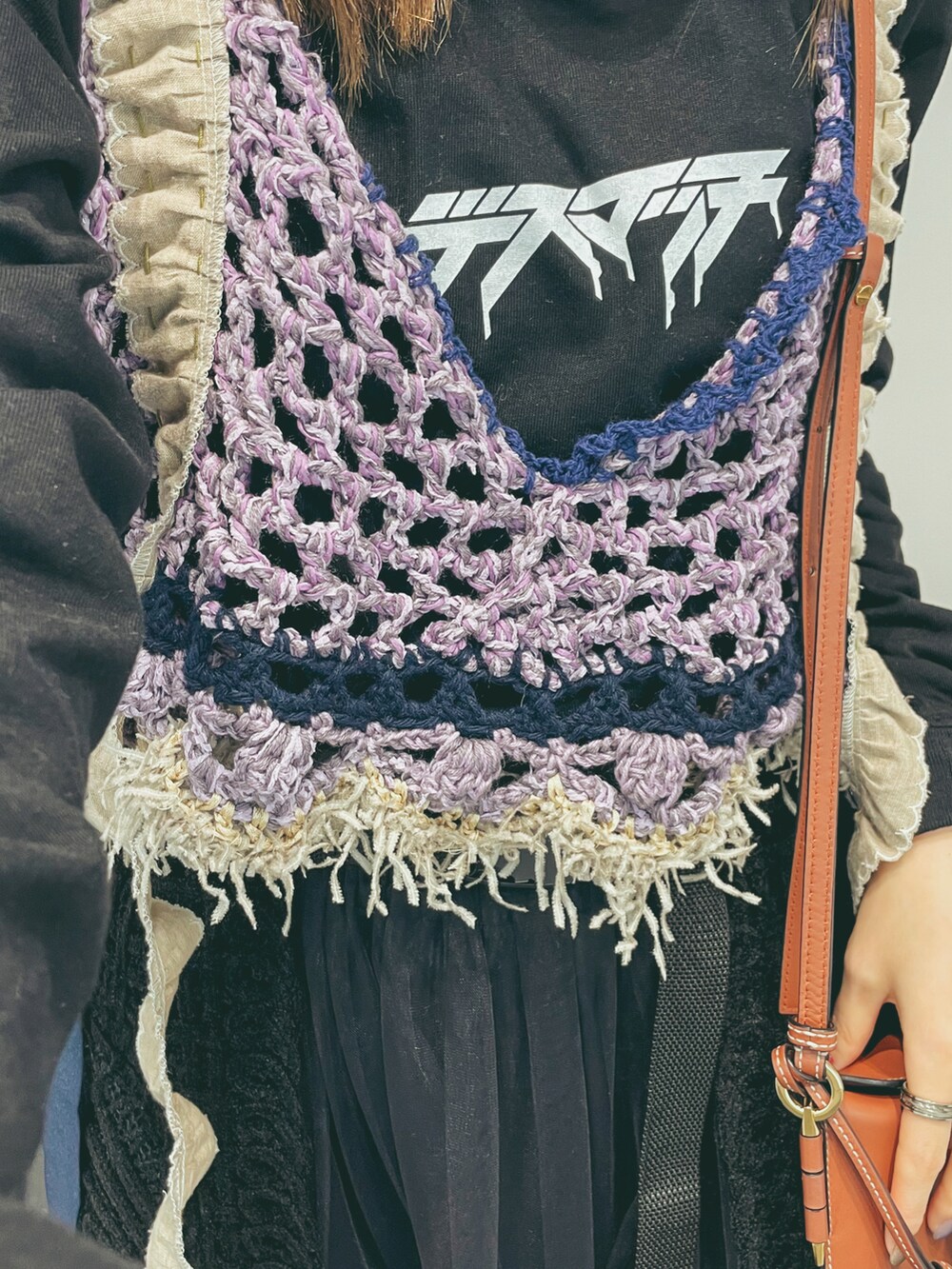 グリーン系のトップス、ブラウン系のショルダーバッグ、ブラック系のスカートを着用したレディースの冬コーディネートの2枚目の写真