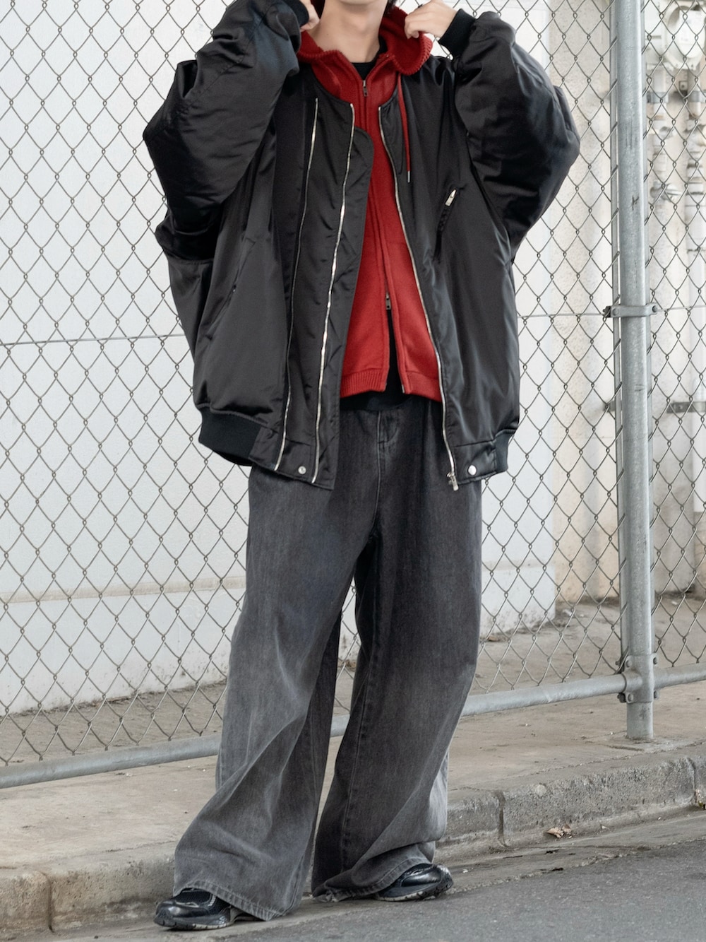 ブラック系のMA-1、レッド系のパーカー、ブラック系のデニムパンツを着用したメンズの秋コーディネートの2枚目の写真