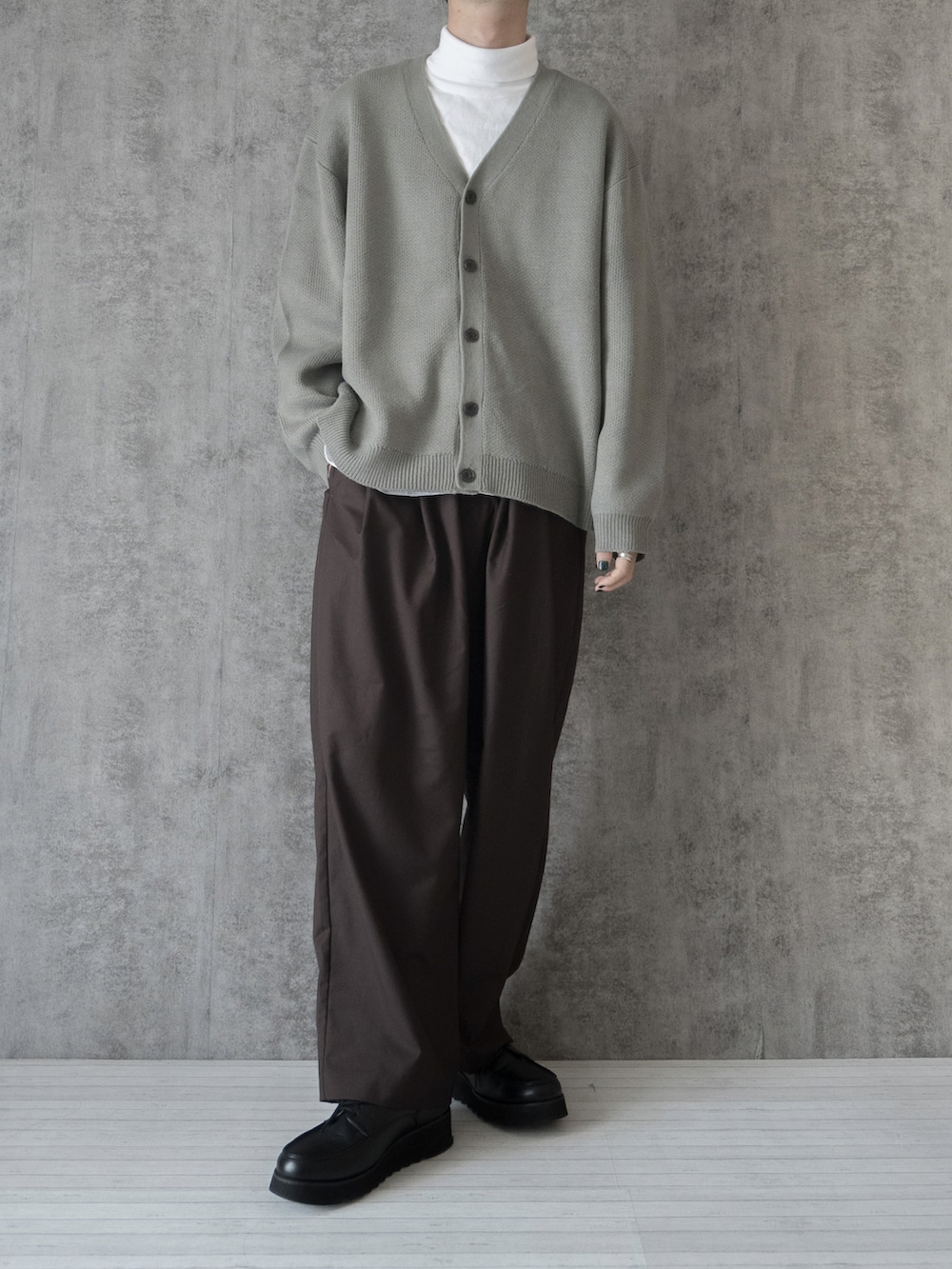 グレー系のカーディガン/ボレロ、ホワイト系のTシャツ/カットソー、ブラウン系のスラックスを着用したメンズの冬コーディネートの4枚目の写真