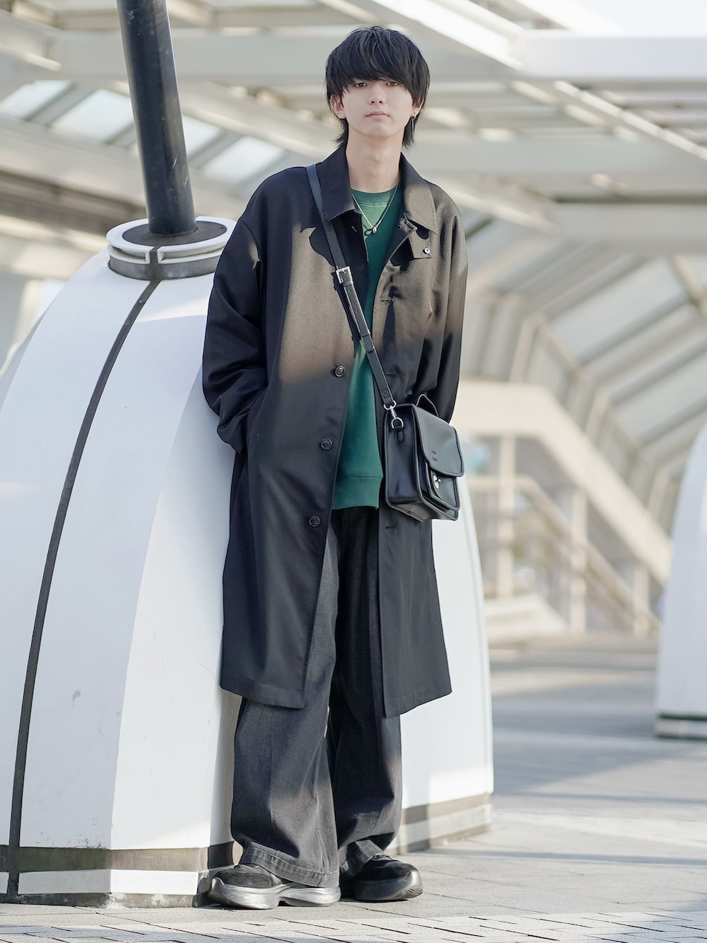 ブラック系のステンカラーコート、グリーン系のスウェット、ブラック系のデニムパンツを着用したメンズの冬コーディネートの2枚目の写真