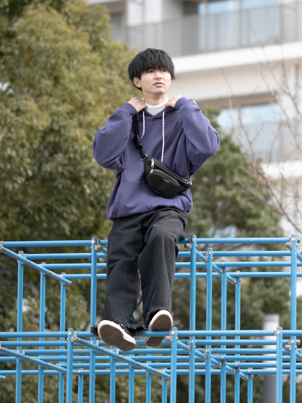 パープル系のパーカー、ブラック系のボディバッグ/ウエストポーチ、ブラック系のデニムパンツを着用したメンズの冬コーディネートの2枚目の写真