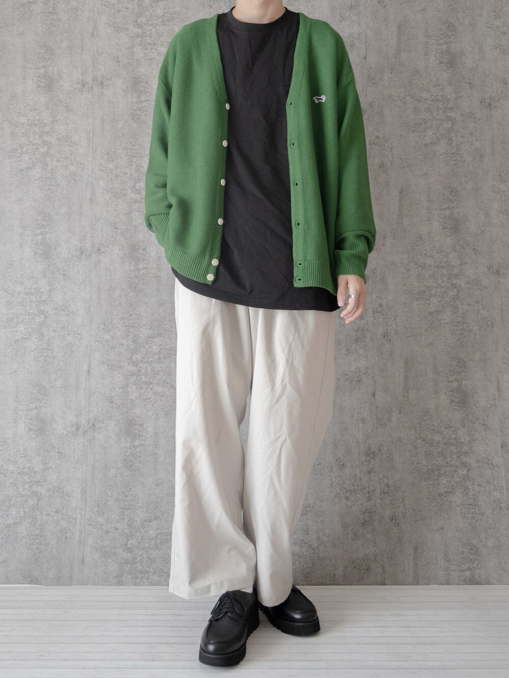 グリーン系のカーディガン/ボレロ、ブラック系のTシャツ/カットソー、ホワイト系のスラックスを着用したメンズの秋コーディネートの3枚目の写真