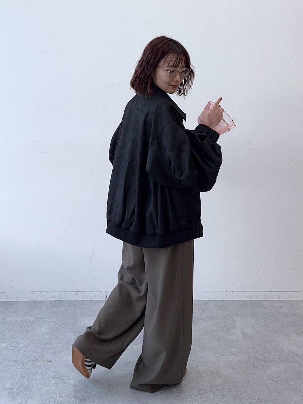 ブラック系のブルゾン、ブラウン系のスラックスを着用したレディースの秋コーディネートの4枚目の写真