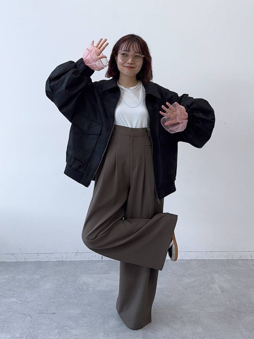 ブラック系のブルゾン、ブラウン系のスラックスを着用したレディースの秋コーディネートの2枚目の写真