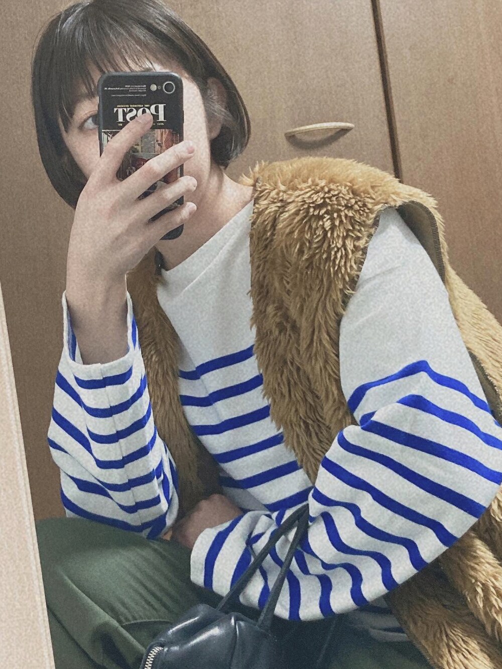 ブラウン系のベスト、ホワイト系のTシャツ/カットソー、ブラック系のボストンバッグを着用したレディースの冬コーディネートの2枚目の写真