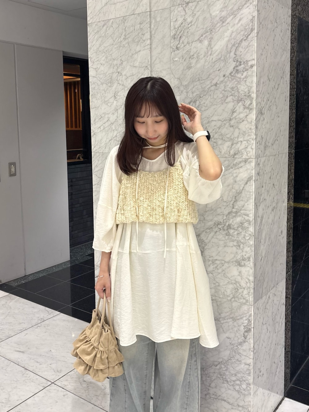 ホワイト系のワンピース、ホワイト系のニット/セーター、ブルー系のデニムパンツを着用したレディースの春コーディネートの6枚目の写真