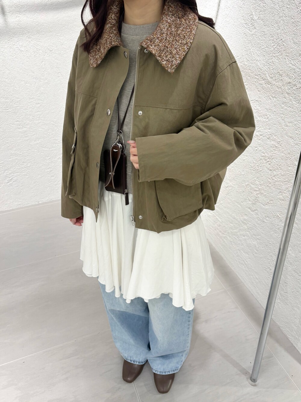 ブラウン系のショルダーバッグ、ベージュ系のスウェット、ホワイト系のワンピースを着用したレディースの冬コーディネートの3枚目の写真