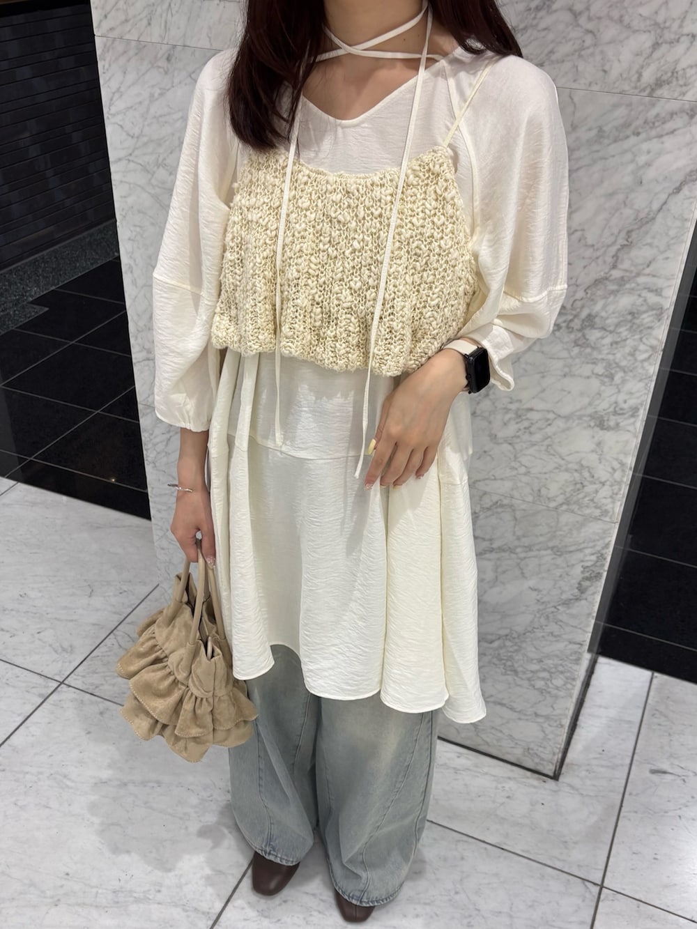 ホワイト系のワンピース、ホワイト系のニット/セーター、ブルー系のデニムパンツを着用したレディースの春コーディネートの5枚目の写真